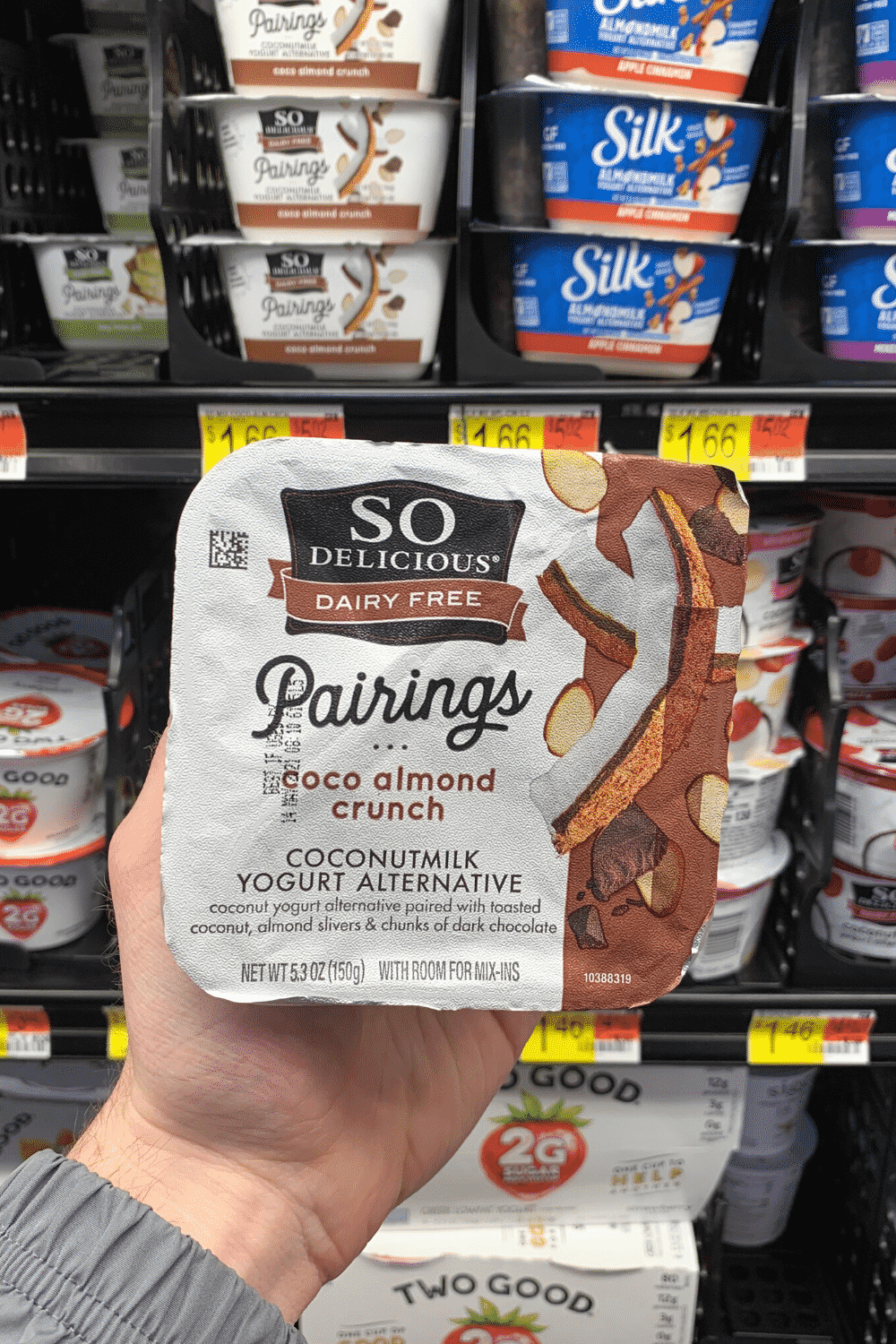 A hand holding so delicious dairy free pairings cocoa almond crunch coconut milk yogurt.