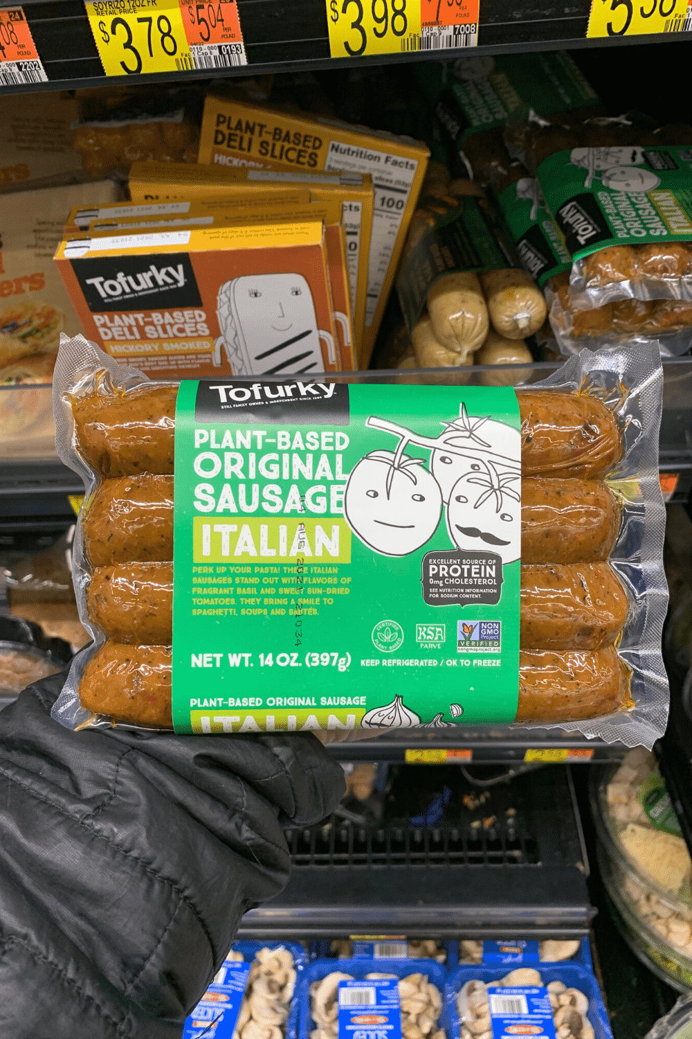 A hand holding Tofurkey plant-based original Italian sausage..