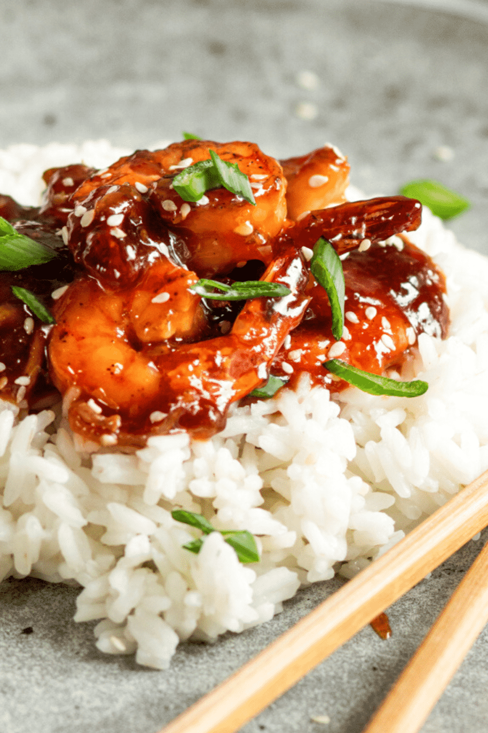 A few pieces of sweet and sour shrimp on a bed of white rice on a gray plate.