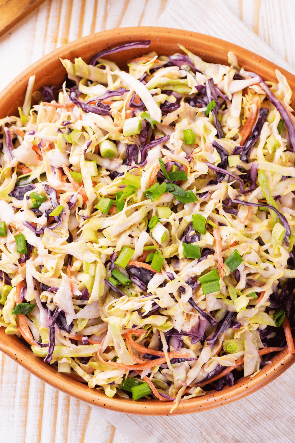 A wooden bowl filled with coleslaw.
