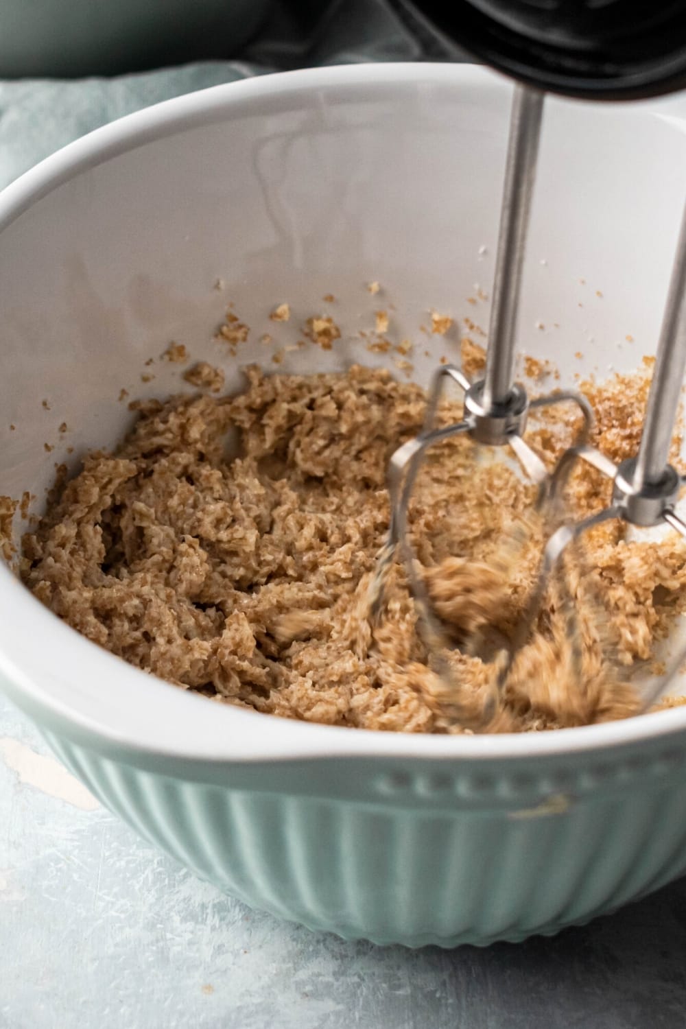 A bowl of cookie dough with an electric mixer mixing it around.