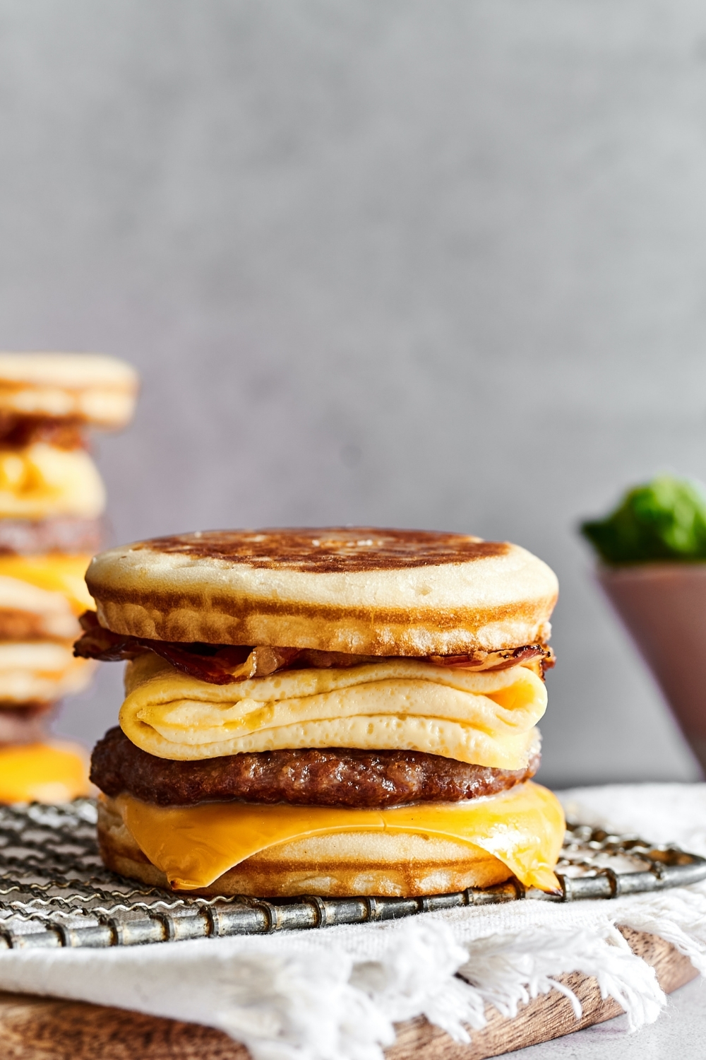 A McGriddle on a wire rack on a White tablecloth cover in a wooden board that is set on a white counter.