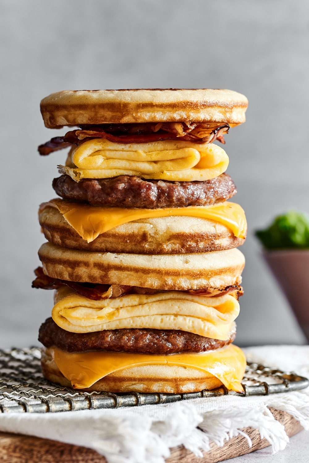 Two McGriddles stacked on top of one another on a wire rack that is on a white tablecloth on a wooden board.