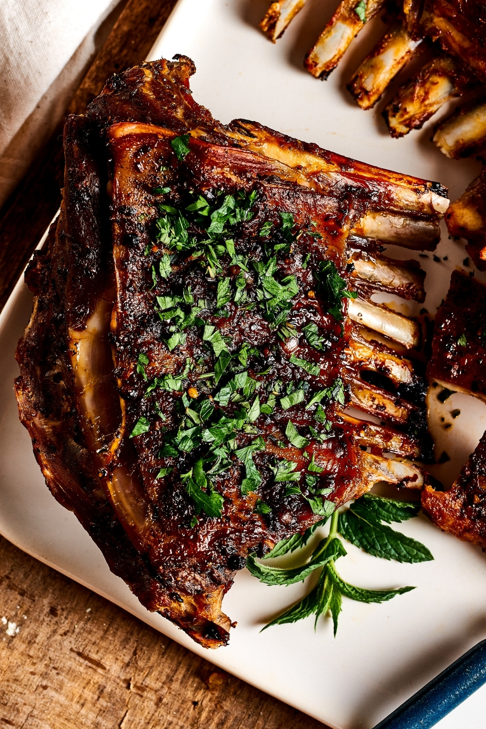 The corner of a white plate with a lamb breast with rib on it.