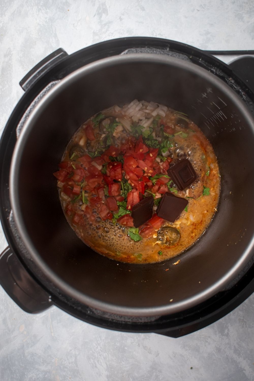 An instant pot filled with enchilada sauce ingredients.
