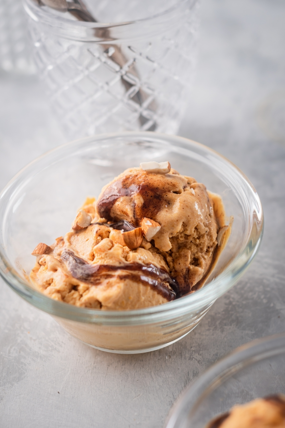A glass bowl on a grey counter filled with two scoops of pumpkin ice cream.