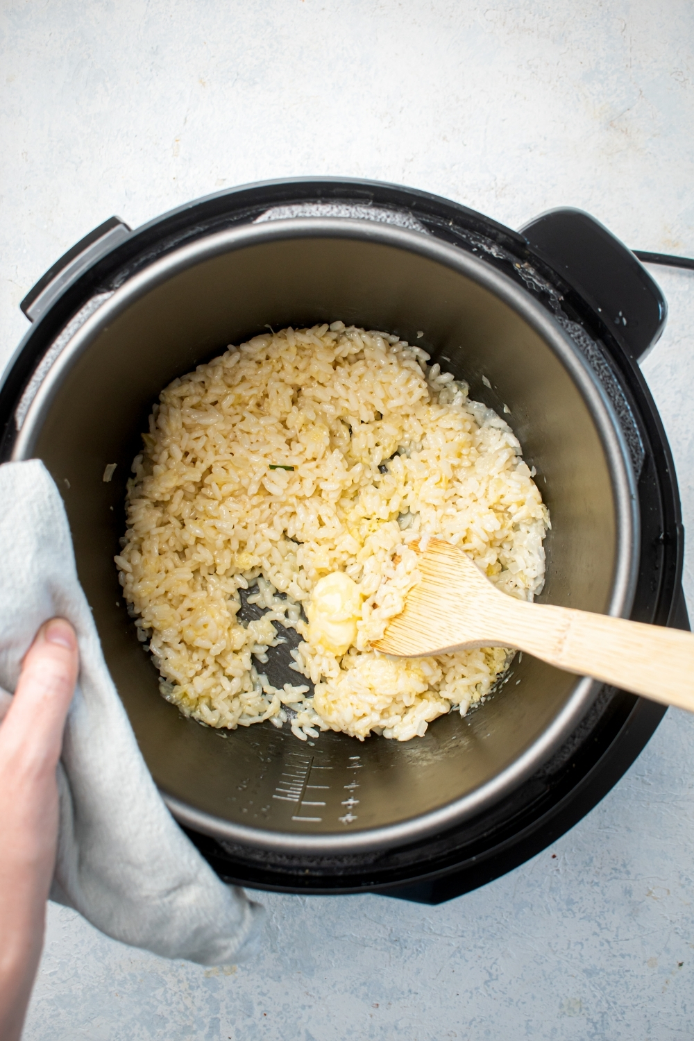 And instant pot filled with risotto with a wooden spoon submerged in it..