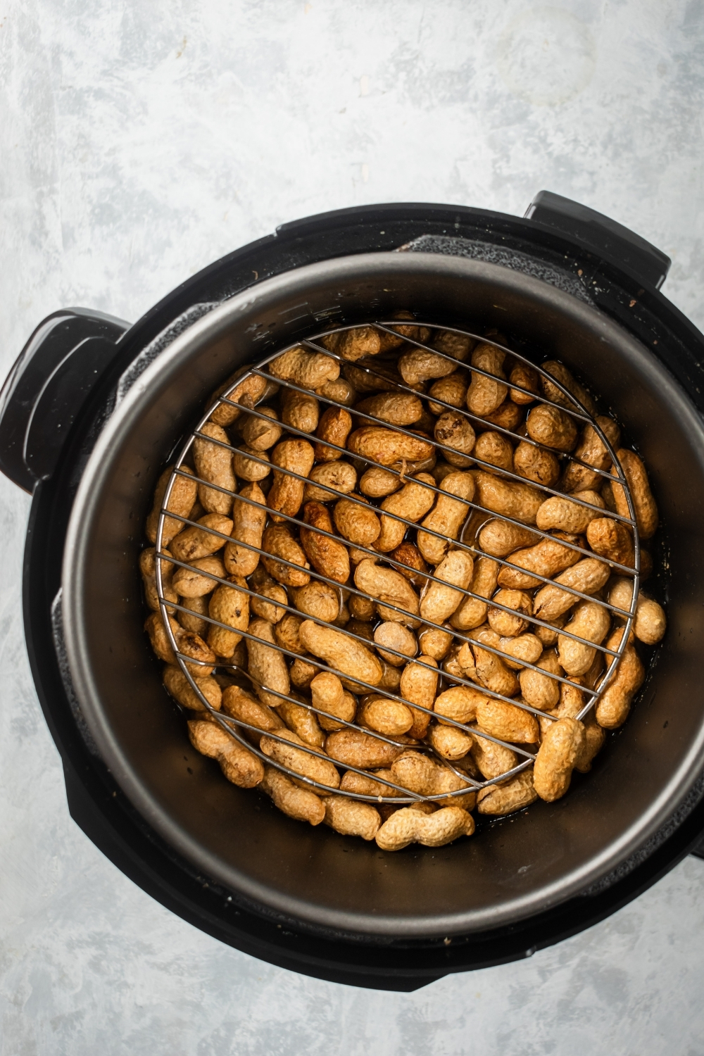Shelled peanuts in an instant pot with wire rack on them.