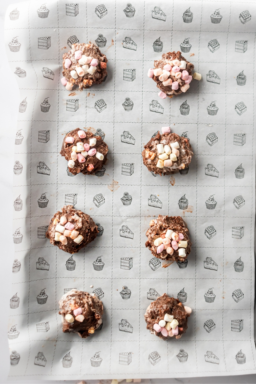 Two rows of four marshmallow cookies on a baking sheet lined with parchment paper.