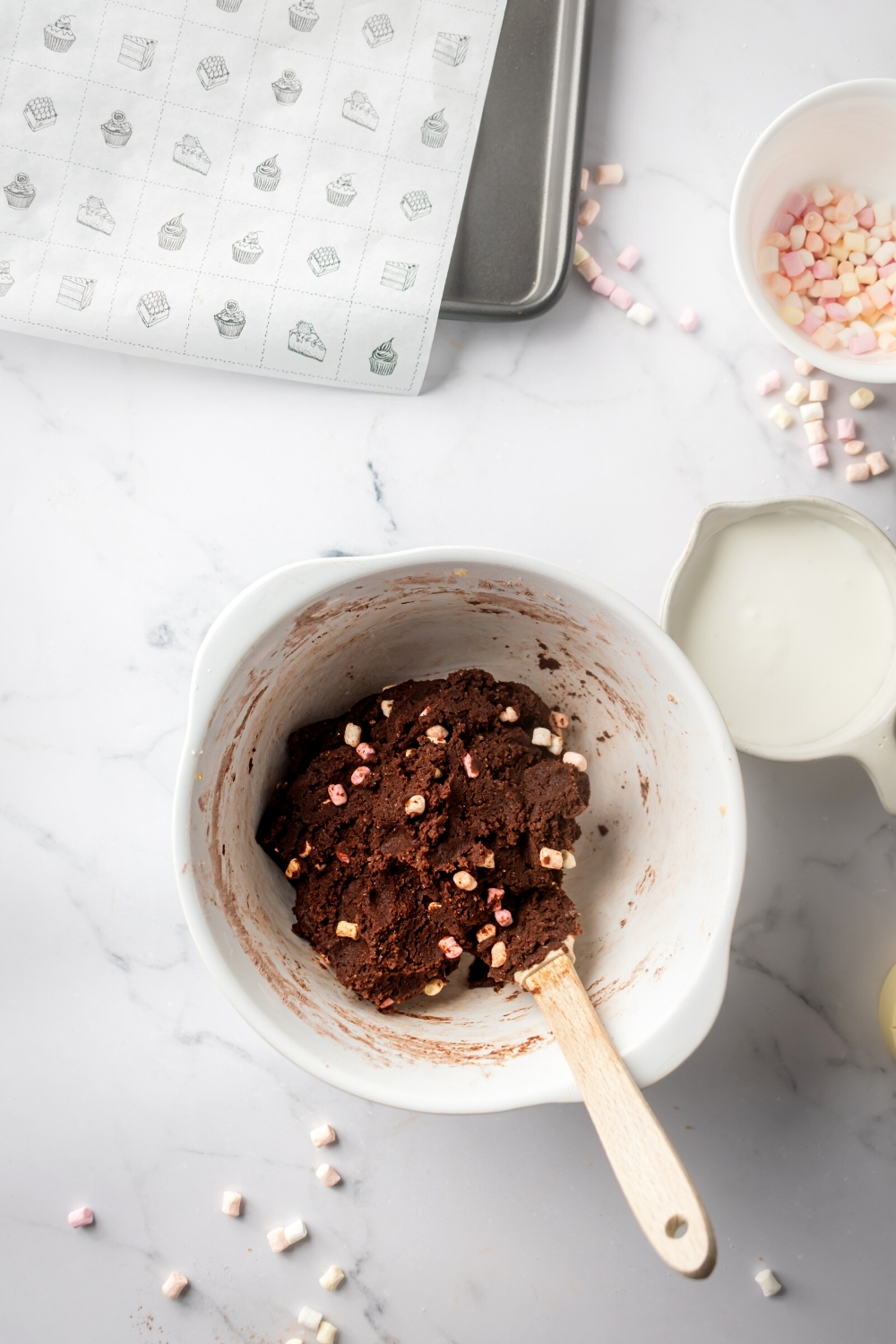 A white mixing bowl with chocolate marshmallow cookie dough in it.