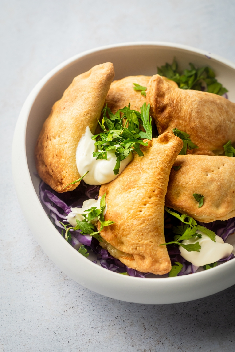 Part of a white bowl filled with five pierogies.