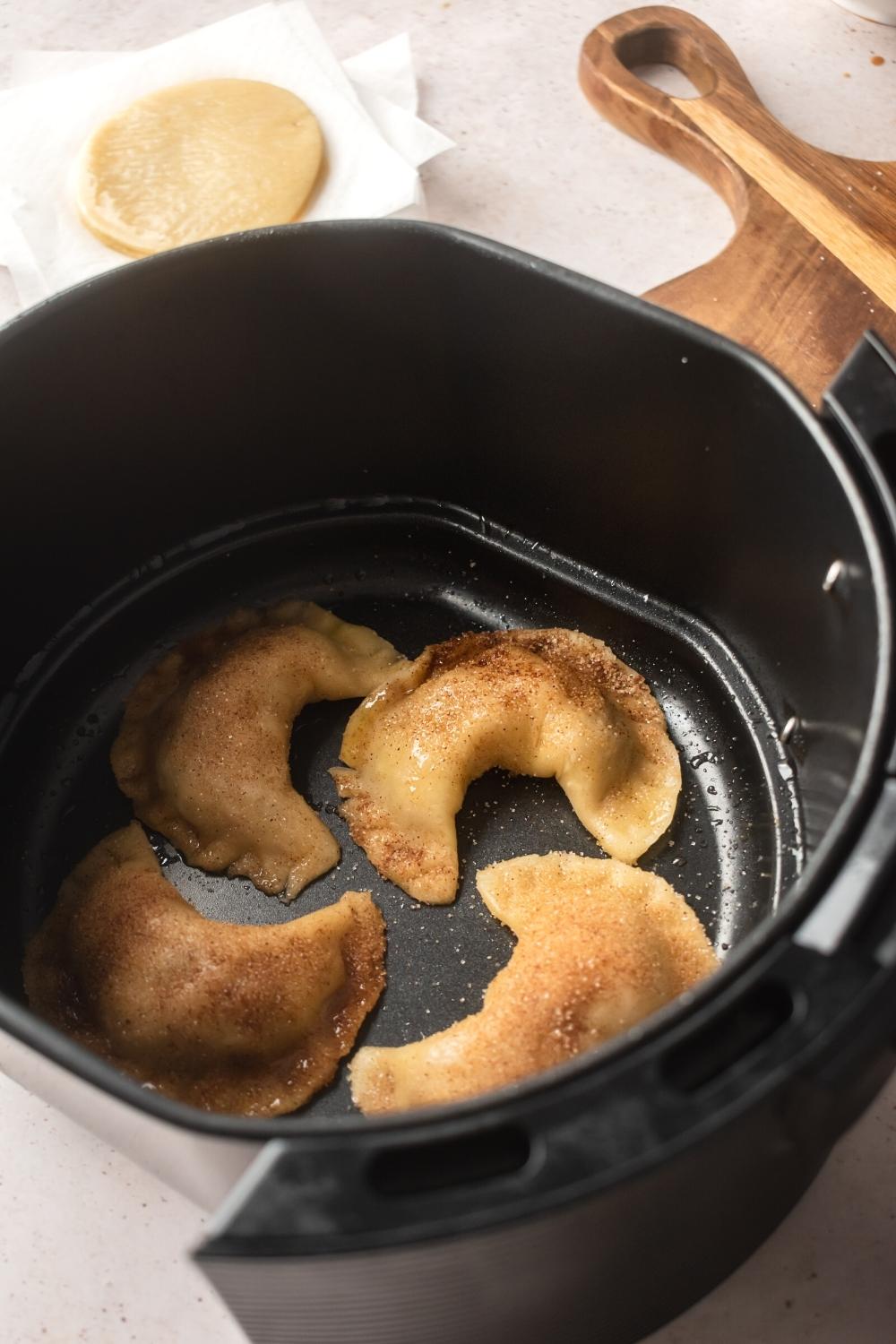 An air fryer filled with for Apple empanadas.