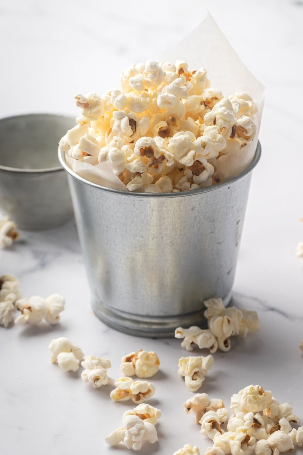 Popcorn in a tin cup on a grey counter.