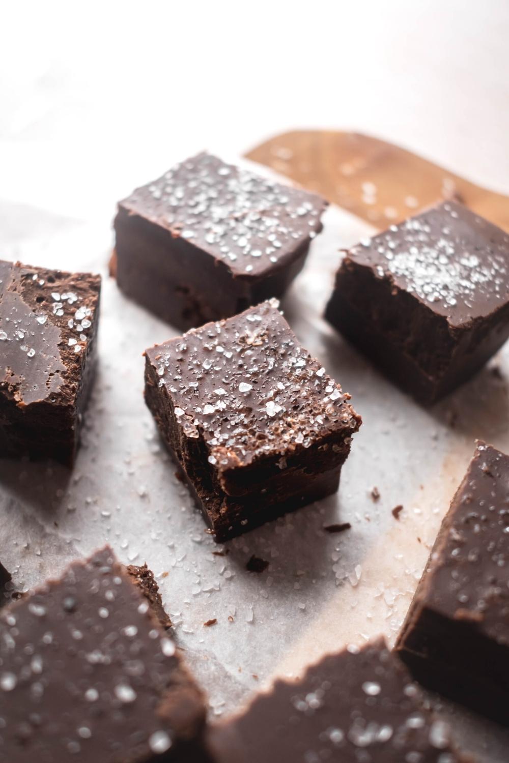 A few squares of chocolate fudge on a piece of parchment paper.