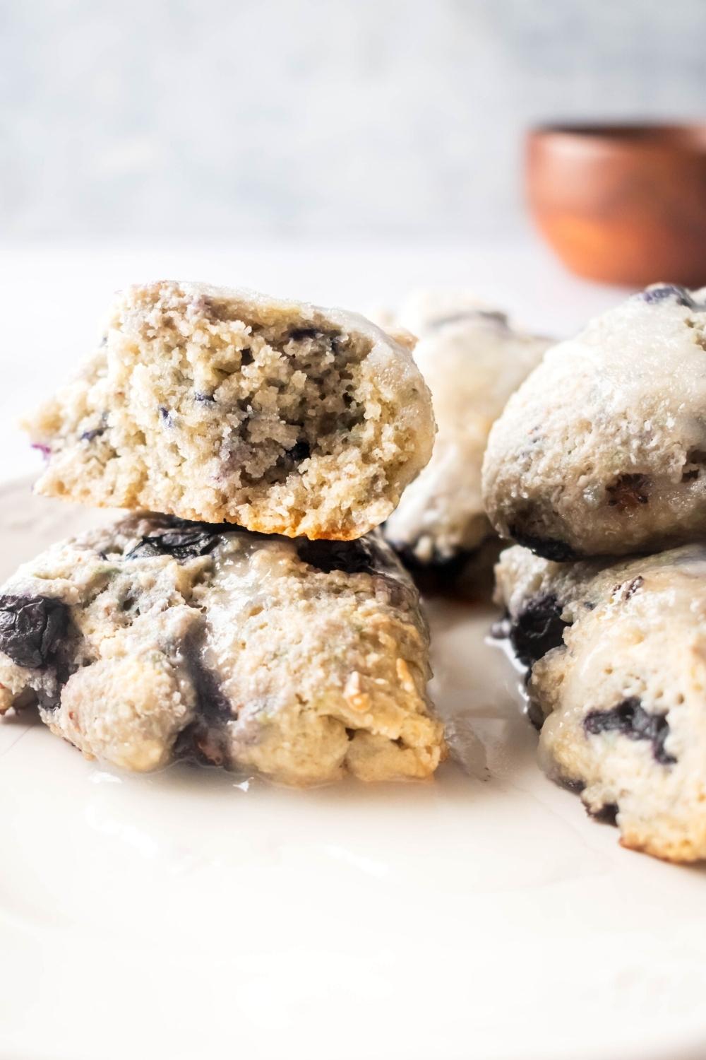 Half of a blueberry scone on top of another scone with parts of more scones to the right of it.