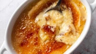 Crème brûlée and a large white ramekin with a spoon submerged in it.