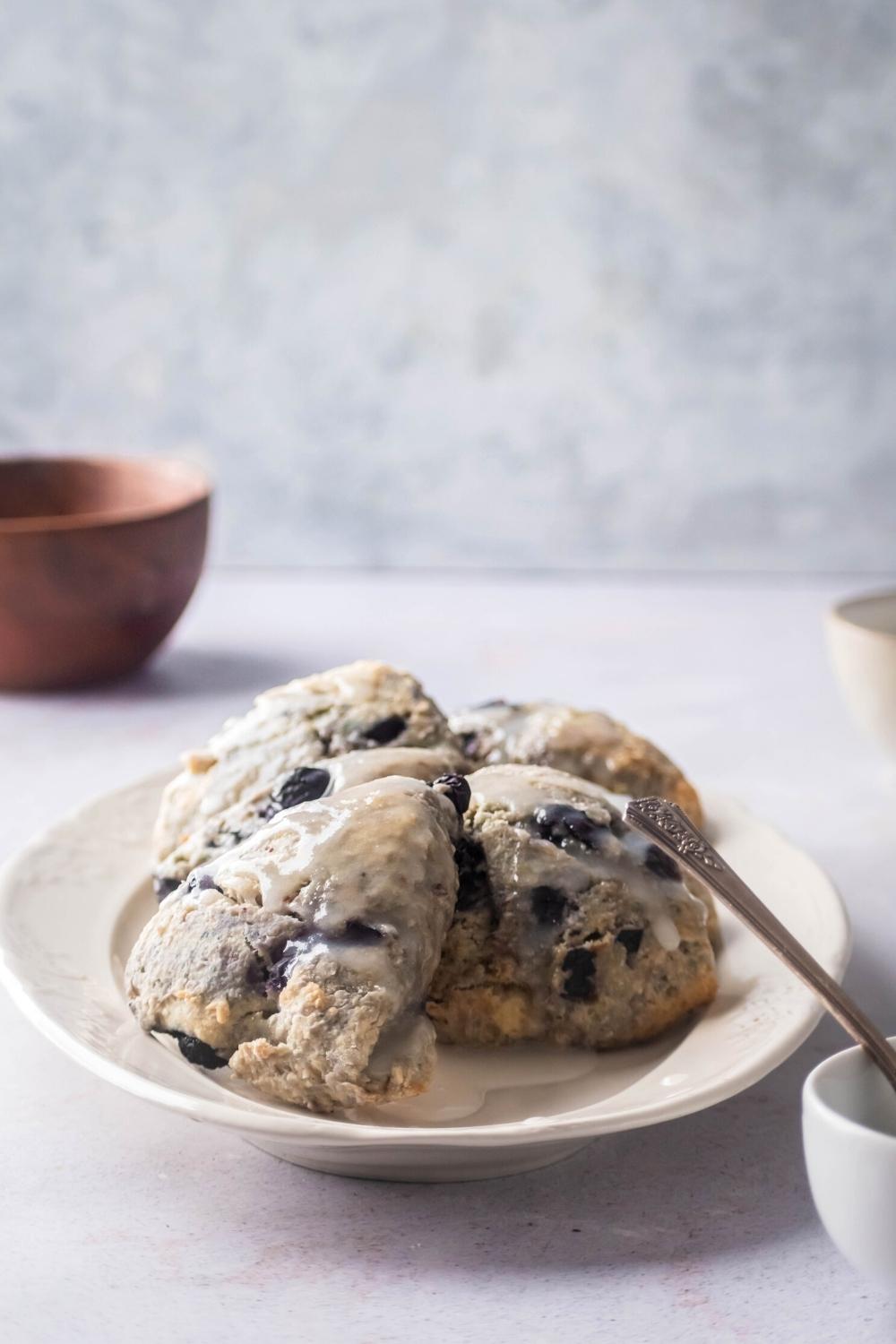 A couple of glazed blueberry scones on a white plate.