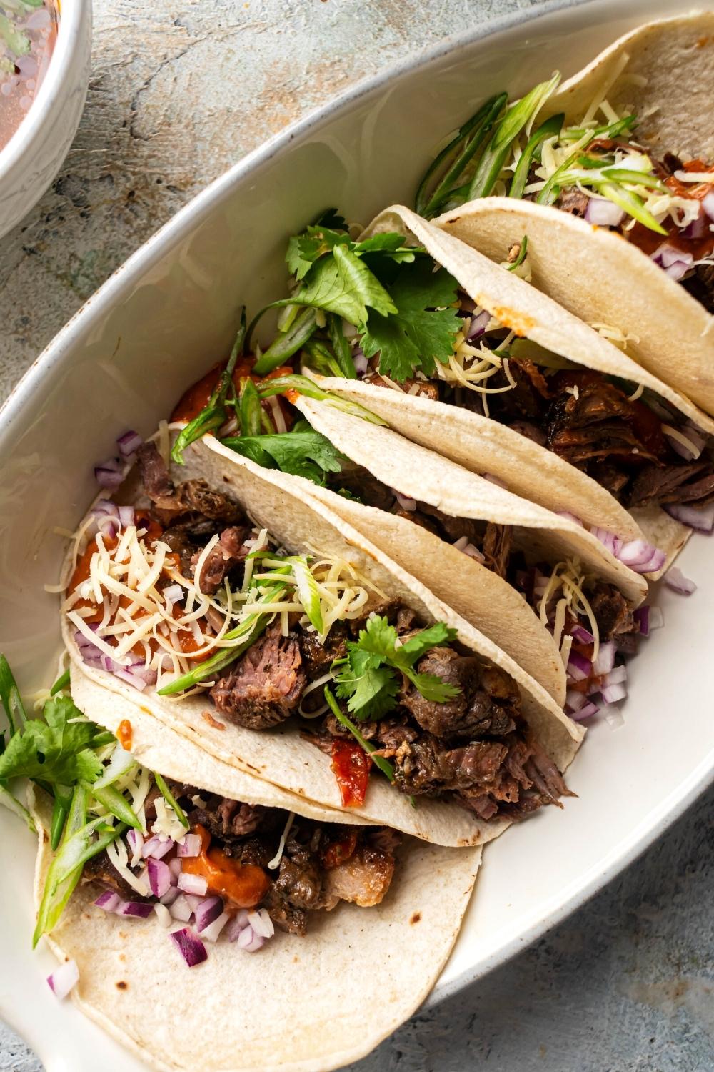 Six Berea tacos in part of a white serving bowl.