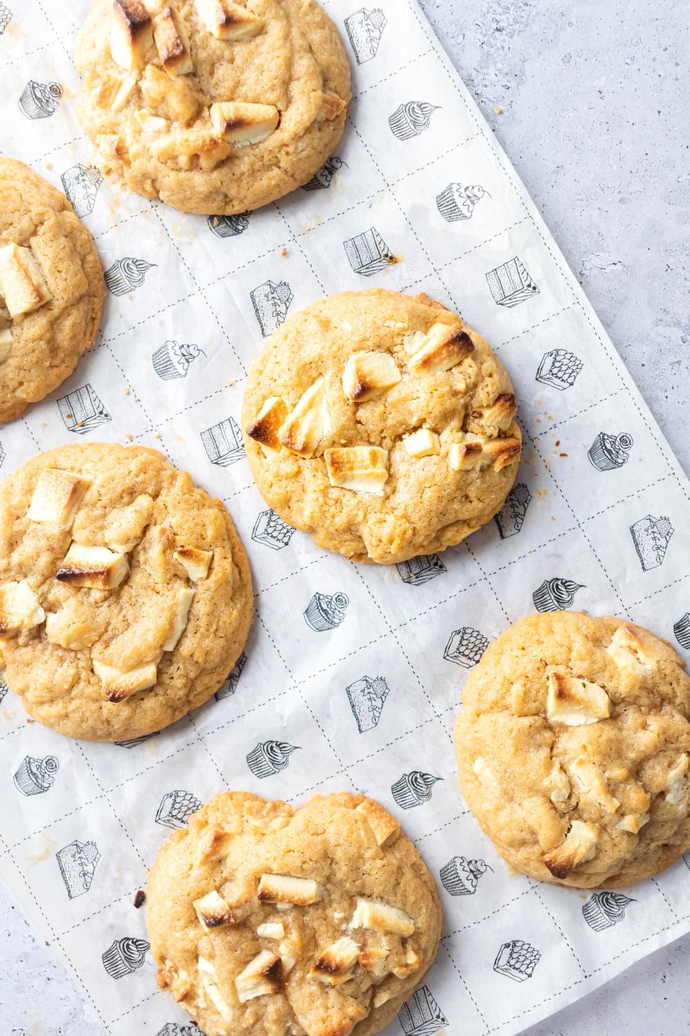 Part of a roll of three cookies with another roll of three cookies to the right of it on a piece of parchment paper on a gray counter.