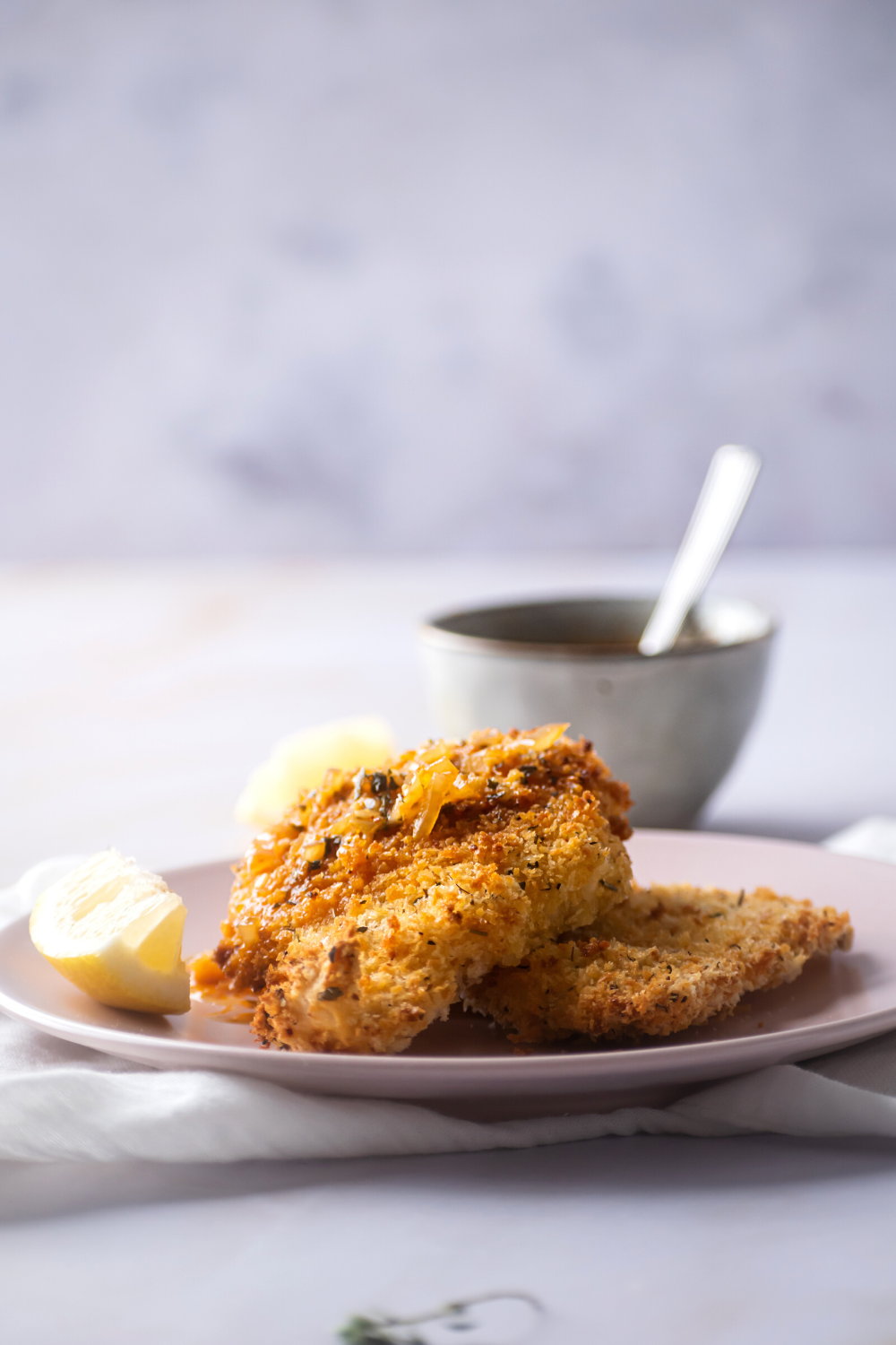 A piece of air fryer catfish wine on another piece of catfish on a pink plate.