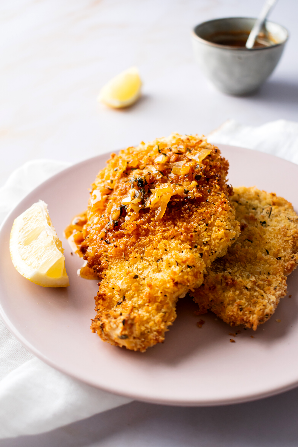 Breaded catfish on top of another piece of bread a catfish on part of a pink plate.