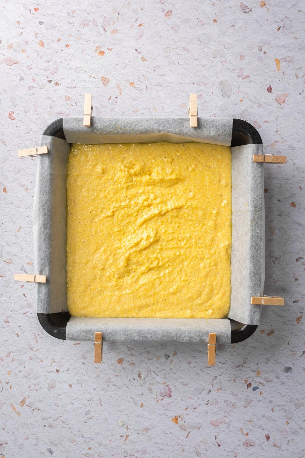 Creamy polenta in a baking tray line with parchment paper.