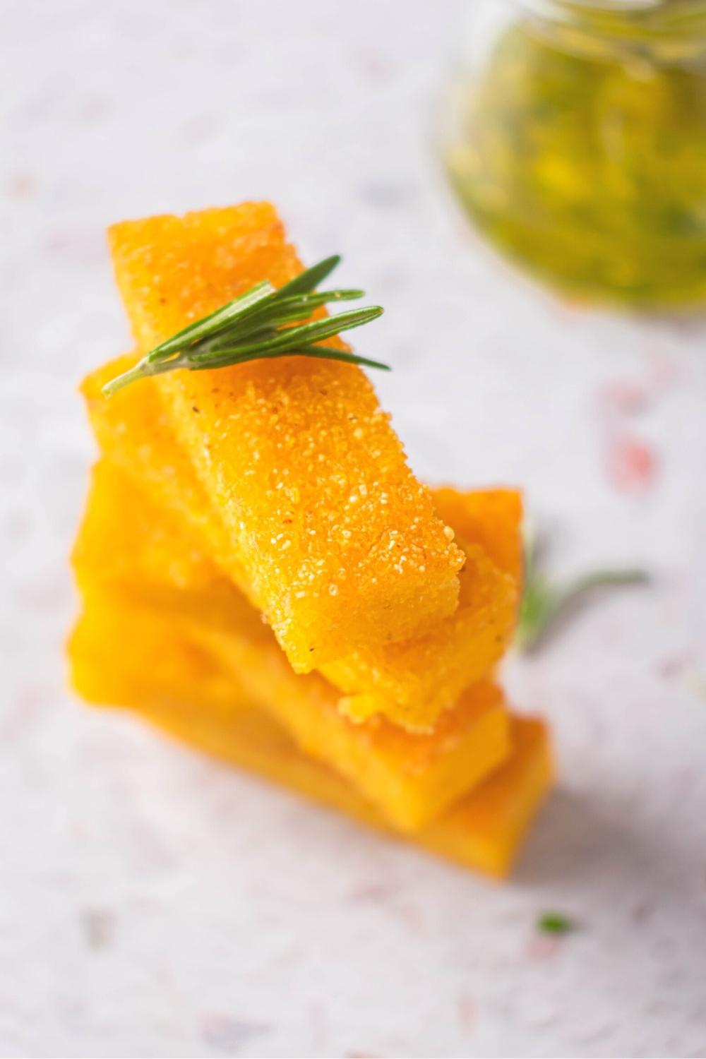 A bunch of polenta sticks stacked on top of one another on a white counter.