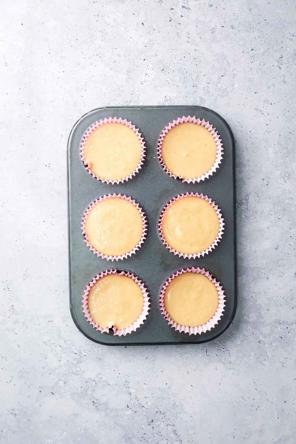 Mochi muffin batter in six muffin tins on a white counter.