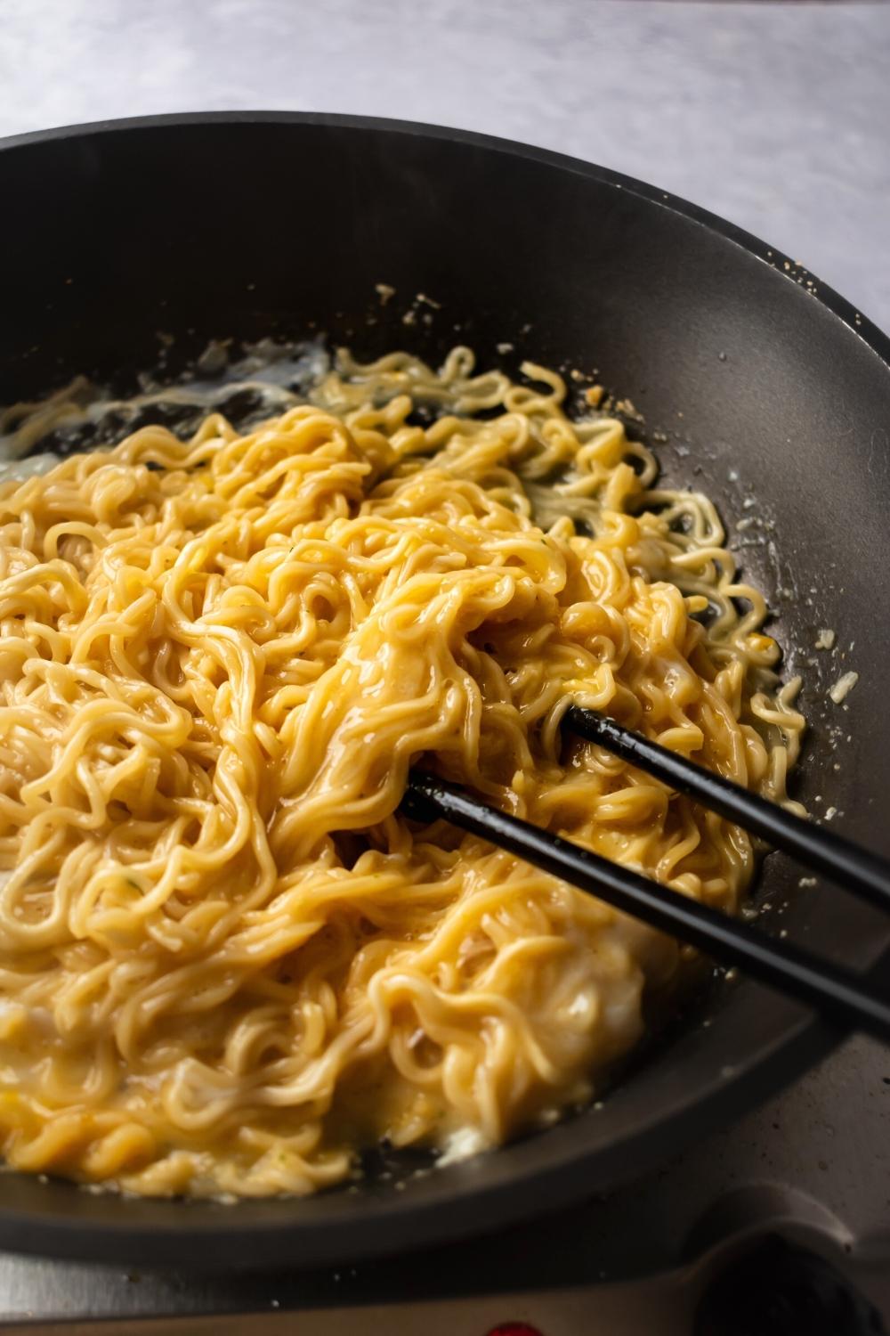 Sebahagian daripada kuali hitam yang dipenuhi dengan mi ramen