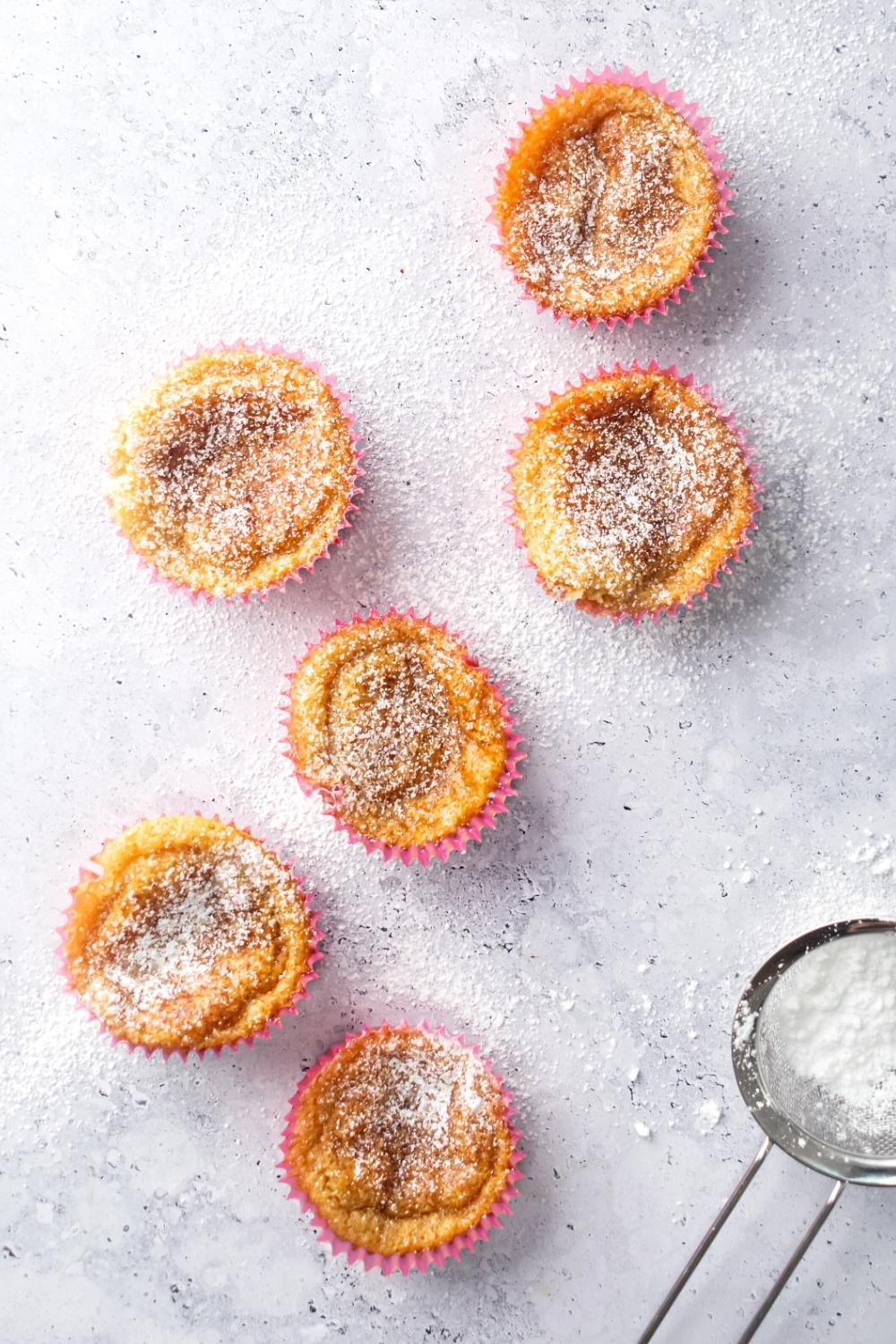 Six mochi muffins scattered on top of a grey counter.