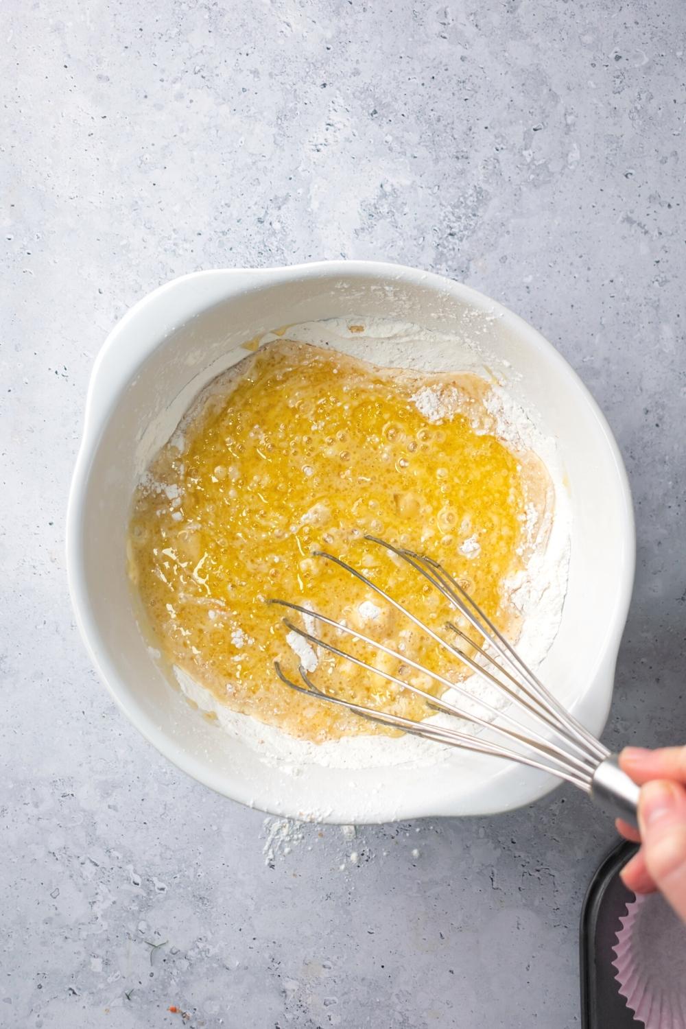 A whisk in a bowl filled with mochi waffle wet and dry ingredients.