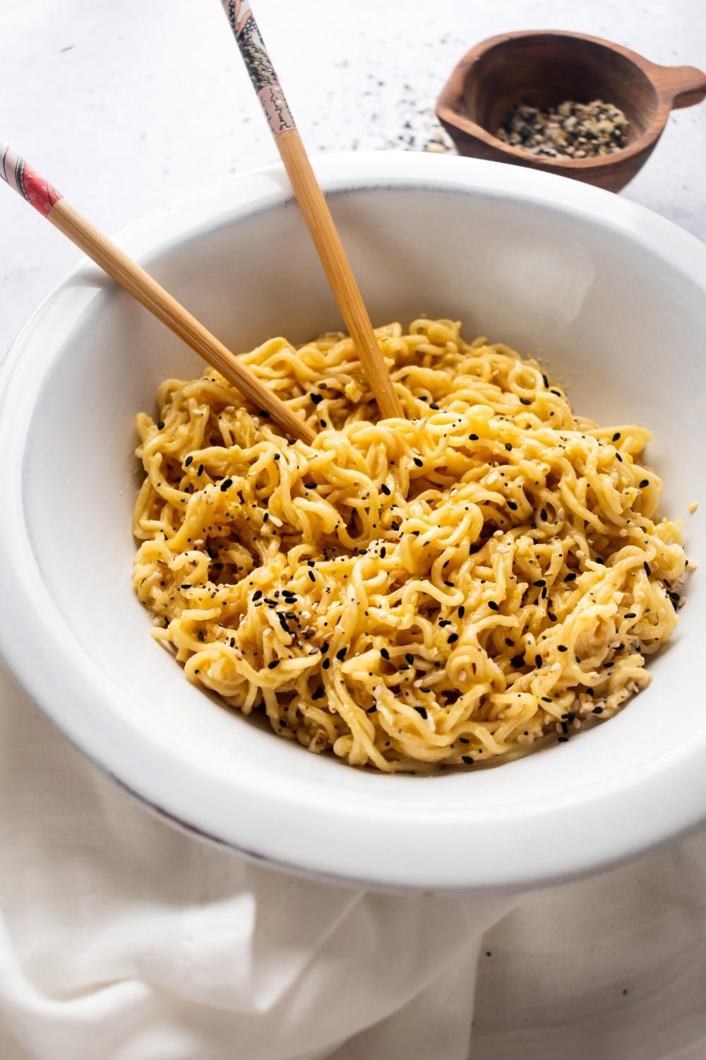 Ramen noodles in a white bowl with part of Chopstix submerged in the noodles.