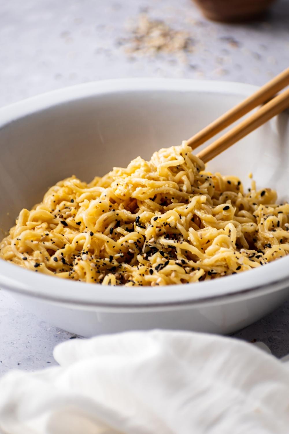 Parte di una ciotola bianca piena di noodles di ramen con bacchette immerse in esse