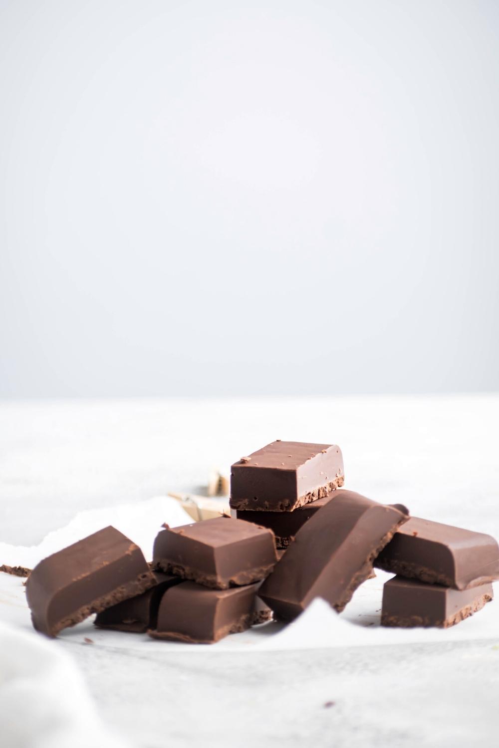 A bunch of Nutella fudge on top of one another on a sheet of parchment paper on a white counter.