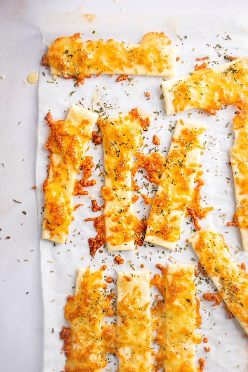 A bunch of cheese sticks on a piece of parchment paper on a white counter.