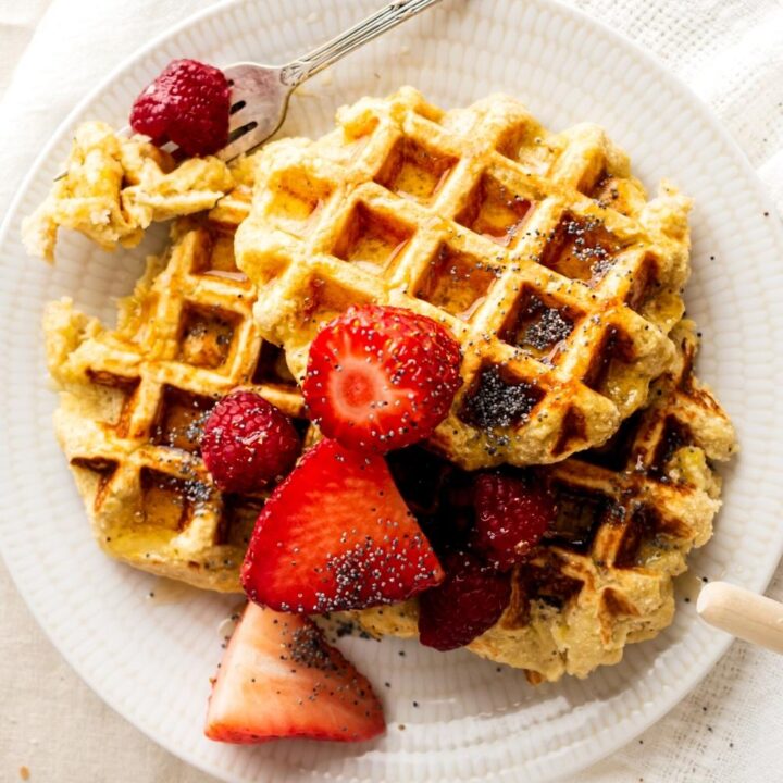 Three healthy waffles overlapping one another with strawberries on top.