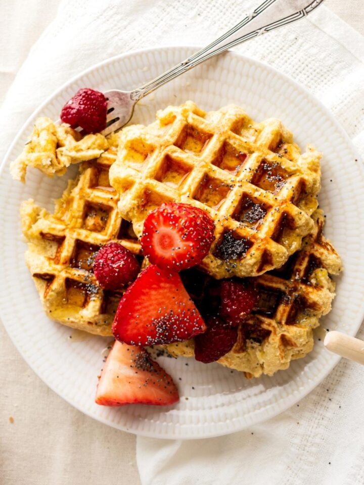 Three healthy waffles overlapping one another with strawberries on top.
