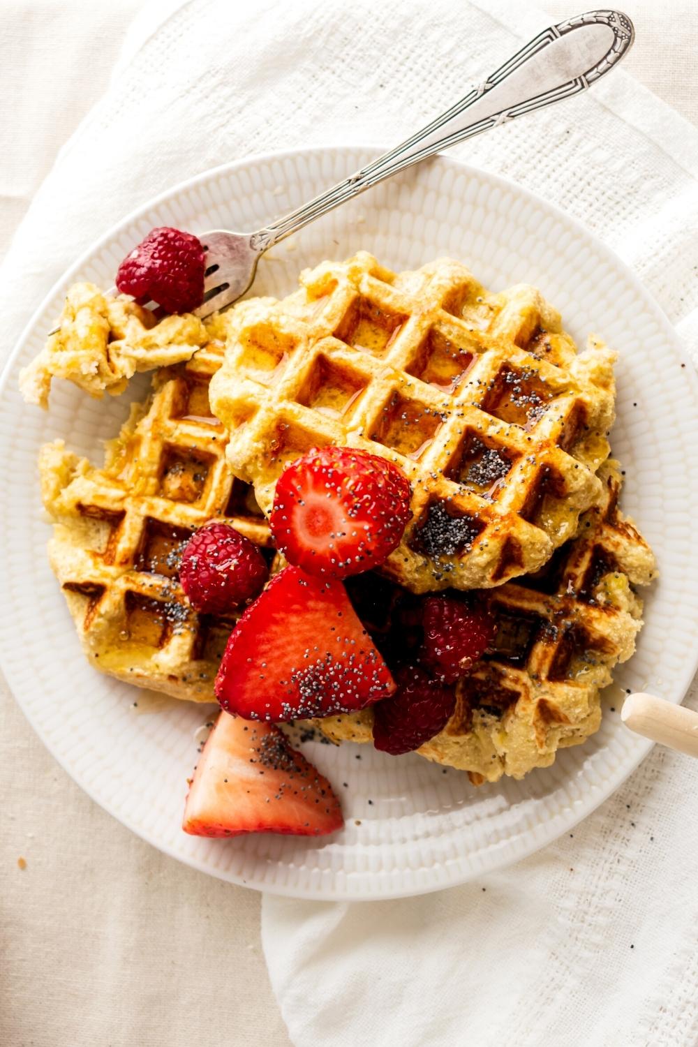 Three healthy waffles overlapping one another with strawberries on top.