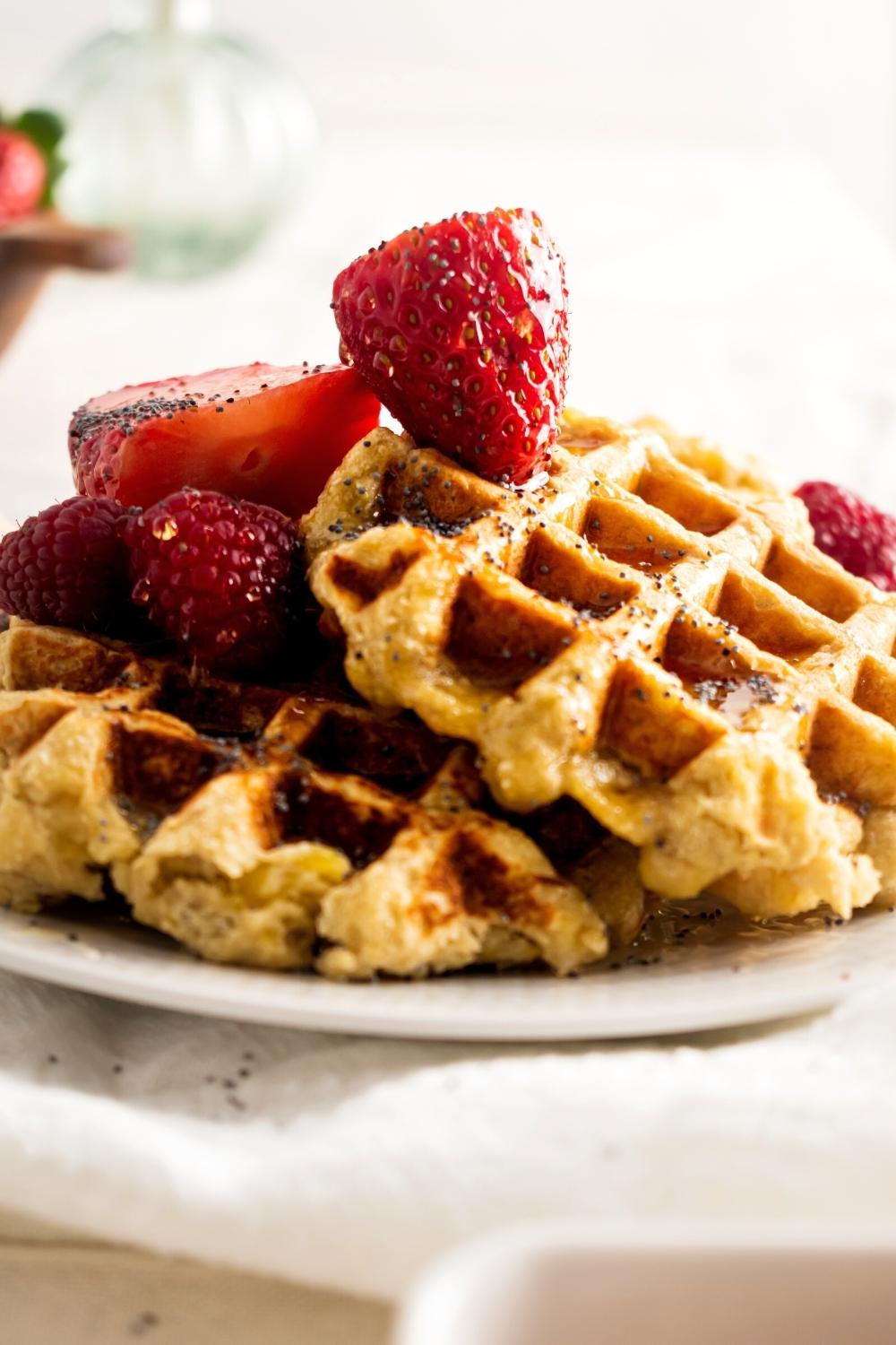 Two homemade waffles that are on one another with strawberries on top.