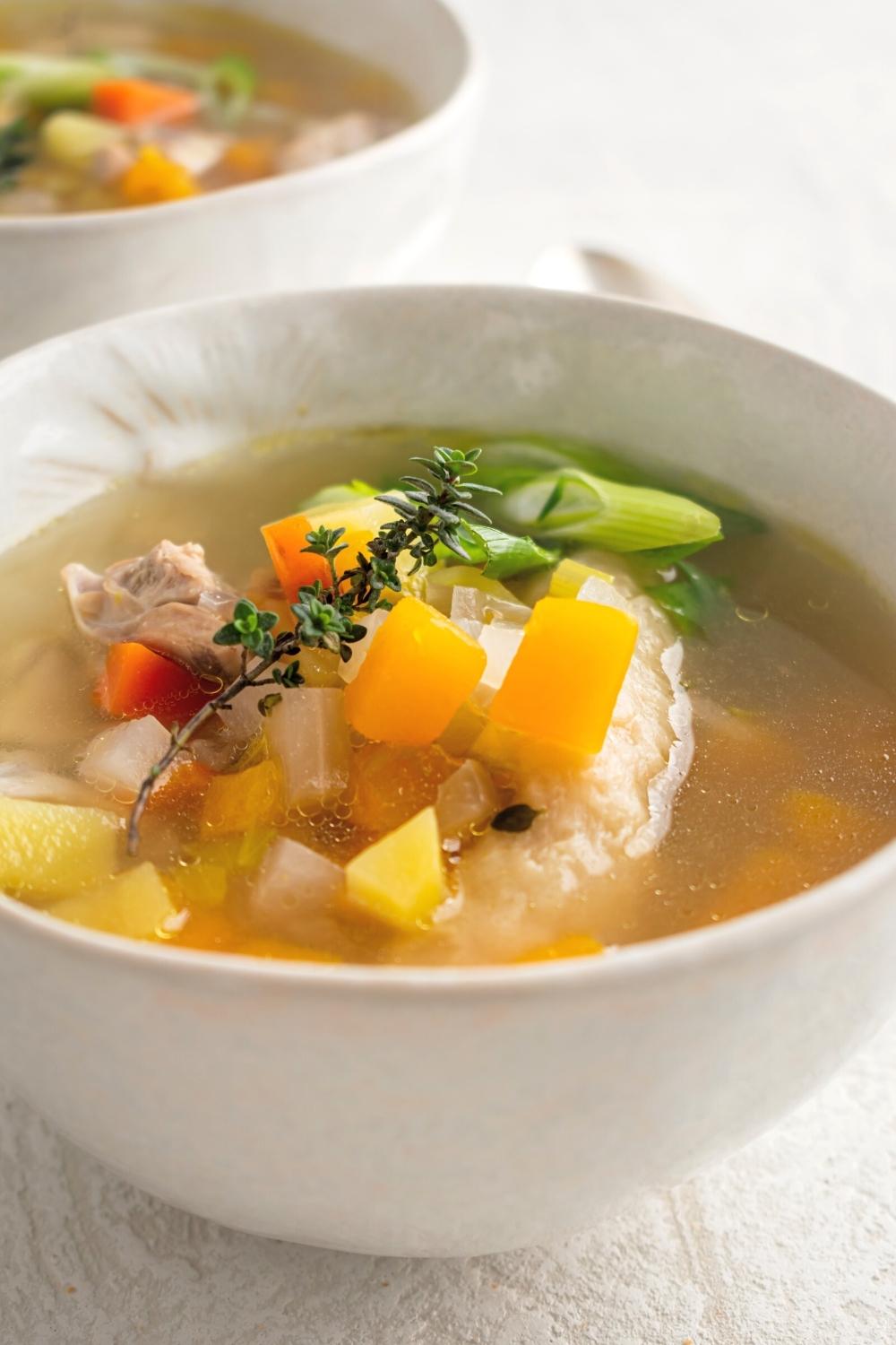 A white bowl that is filled with Jamaican chicken soup.