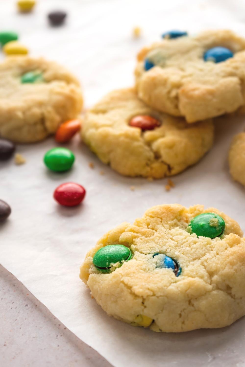 Some Eminem sugar cookies with M&Ms around them all on a piece of parchment paper.