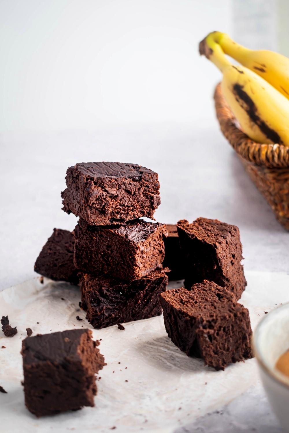 A bunch of three ingredient brownies on top of one another and scattered on a piece of parchment paper.