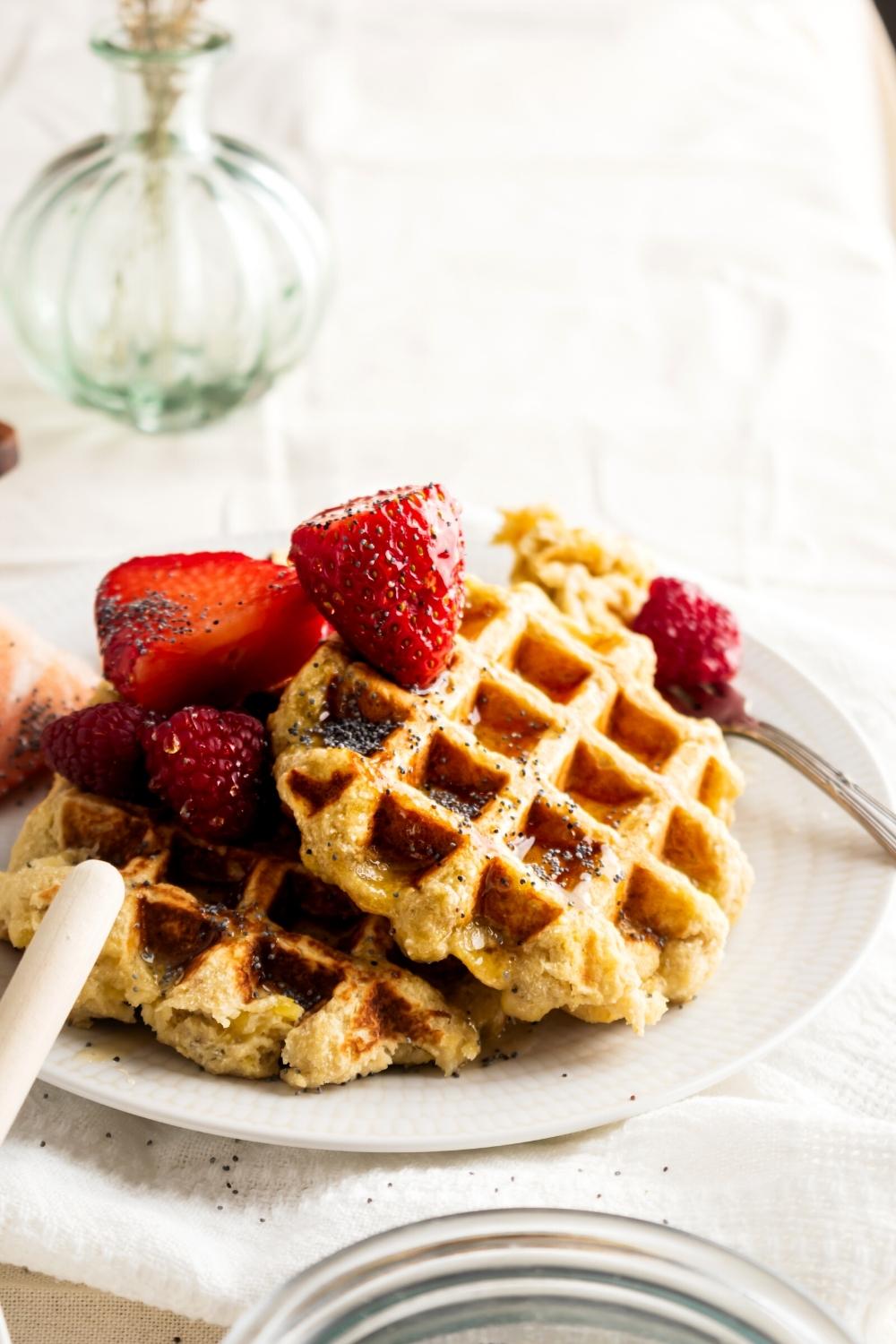 Part of a white plate with three banana waffles on it.