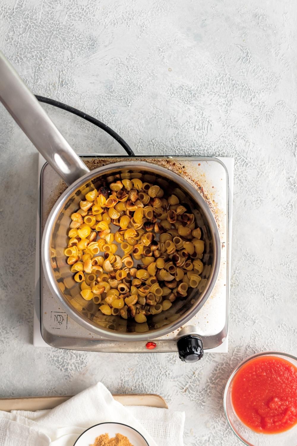 Pasta shells in a pot on top of a burner.