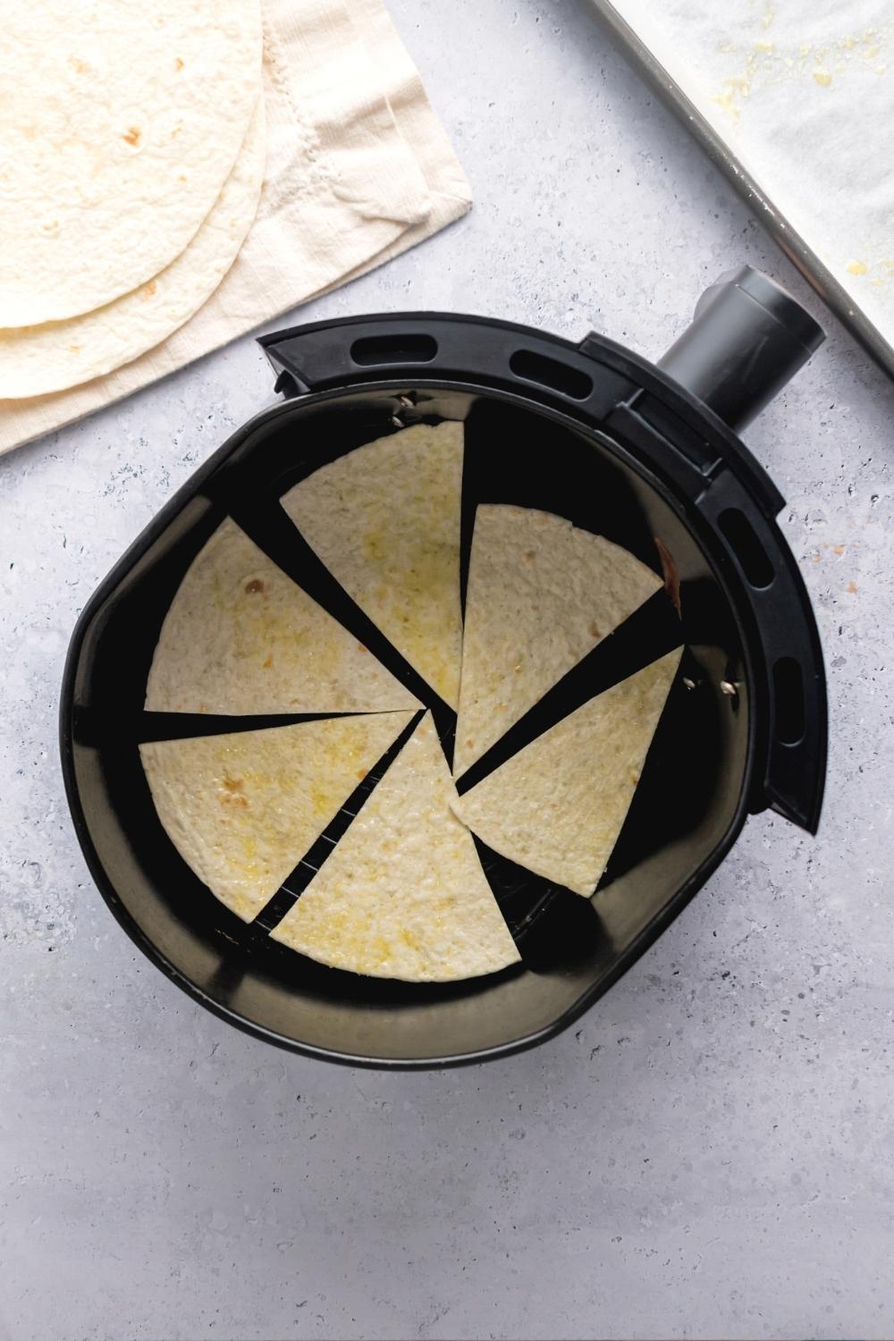 Six triangular pieces of tortilla in an air fryer.