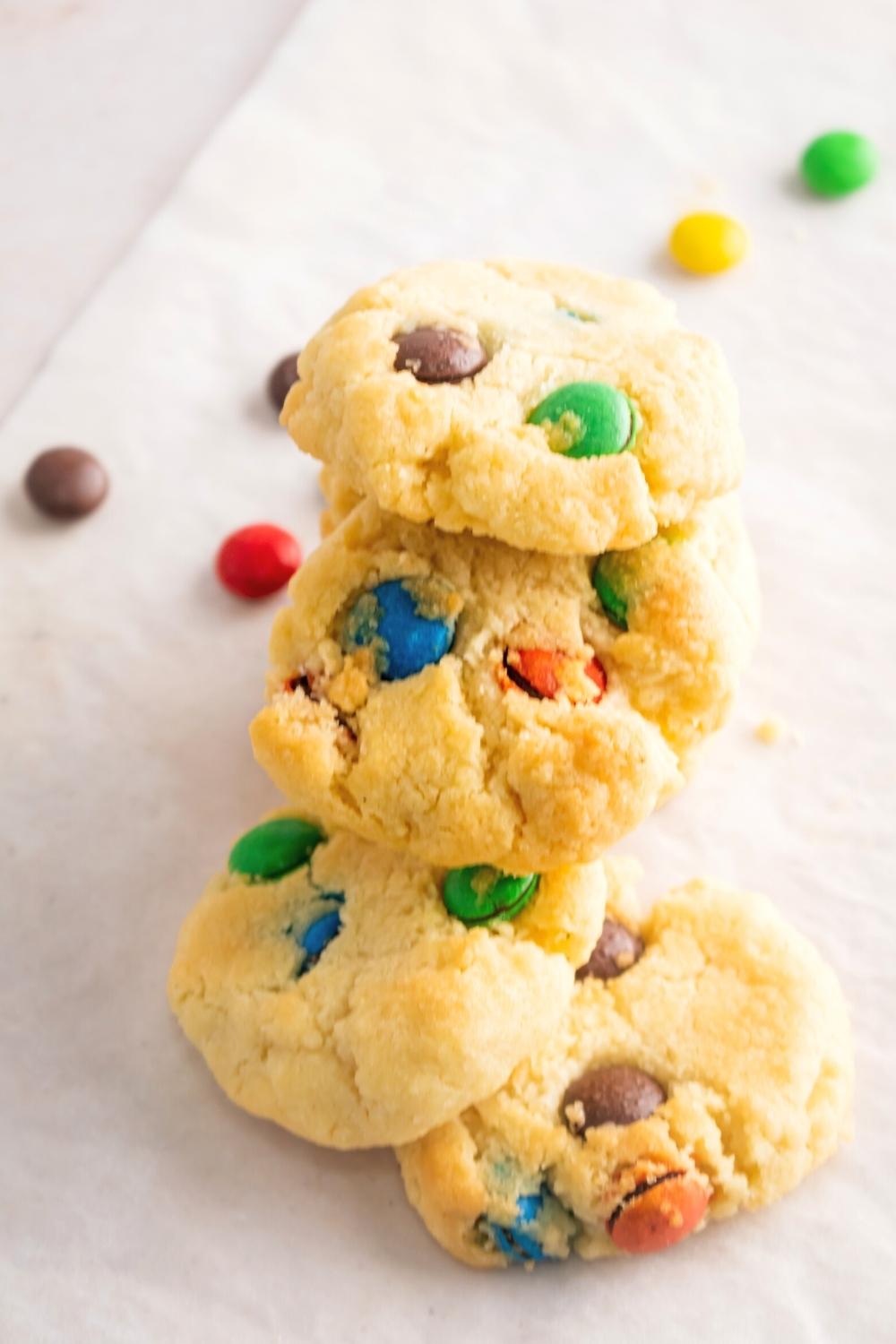 A bunch of Eminem sugar cookies overlapping one another and a sheet of parchment paper.