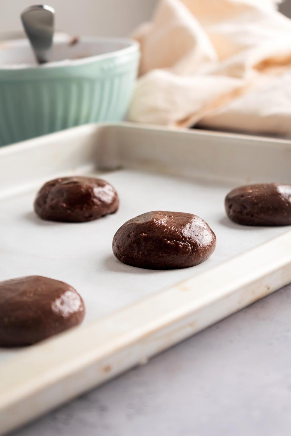 Some Nutella cookie dough balls on a piece of parchment paper on a baking sheet.