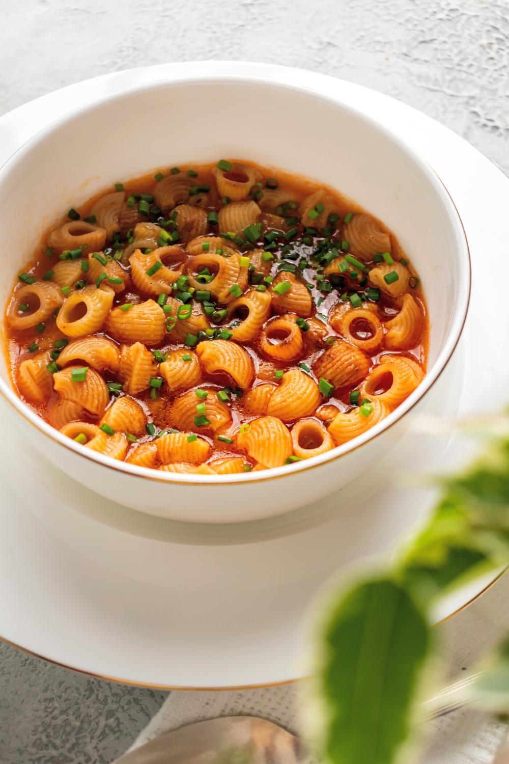 Mexican soup in a white bowl on top of a white plate.