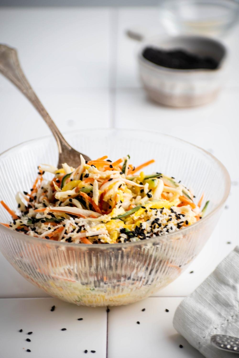 Kani salad in a glass bowl on a white tile counter.