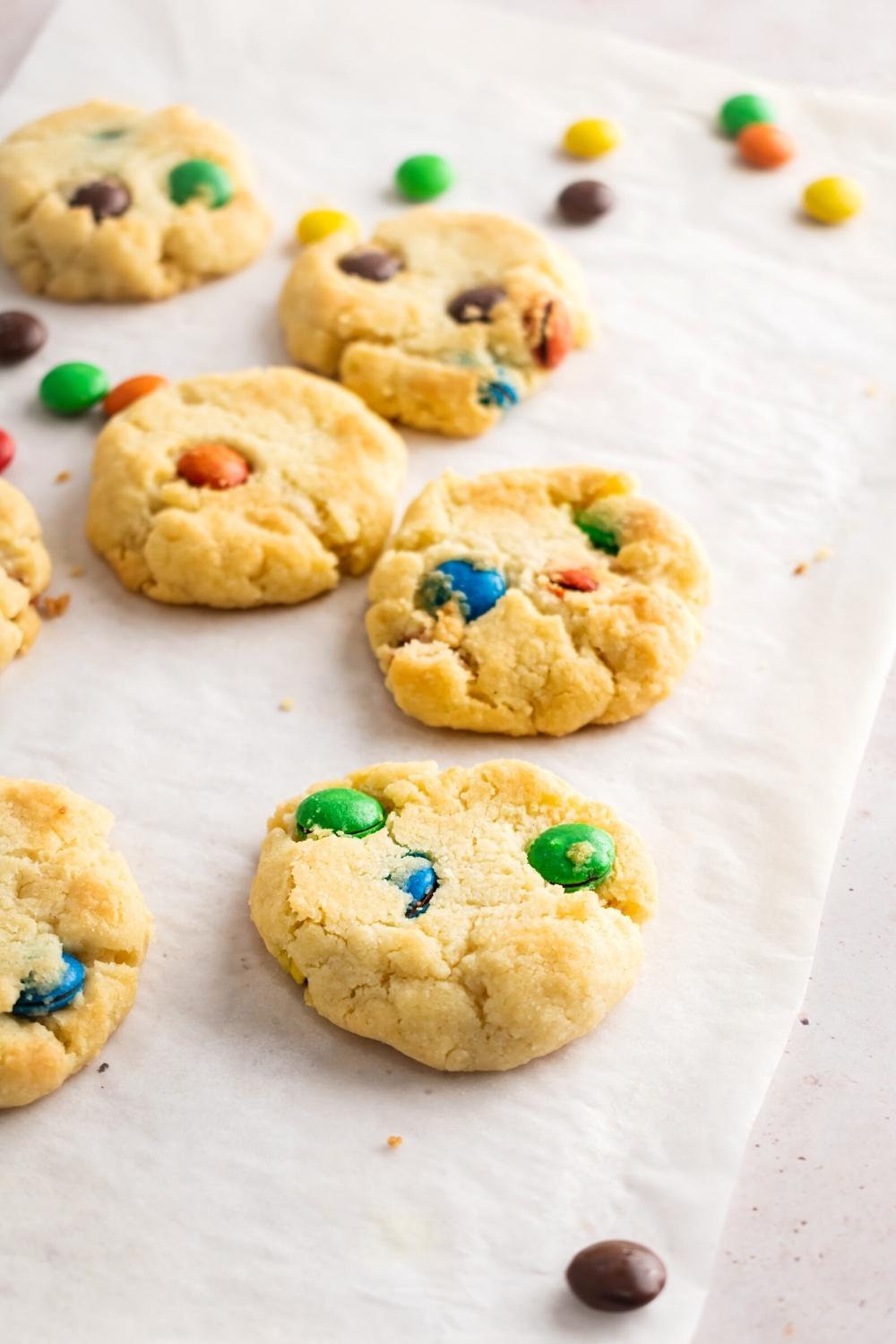 Three ingredient sugar cookies with M&Ms on a piece of parchment paper with some M&Ms on it.
